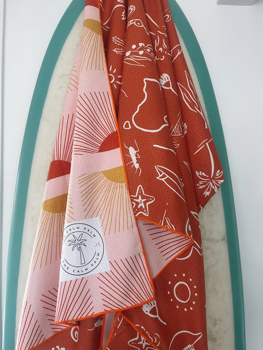 A beach towel with a pattern featuring beach-themed graphics, draped over the back of a chair.