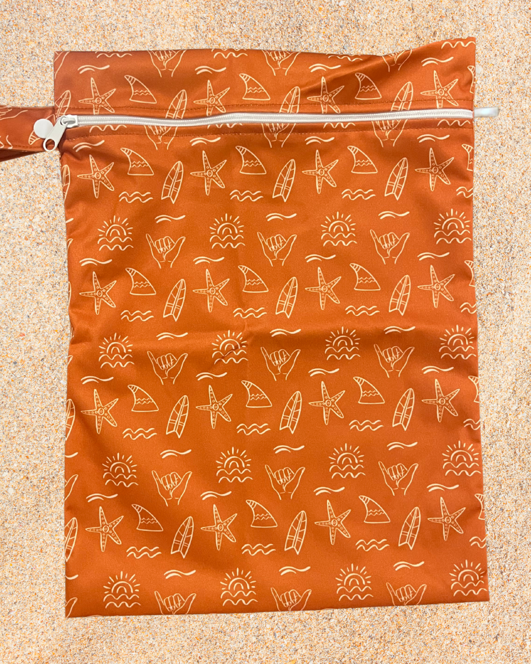 Orange zip wet bag with beach-themed pattern on a beige background