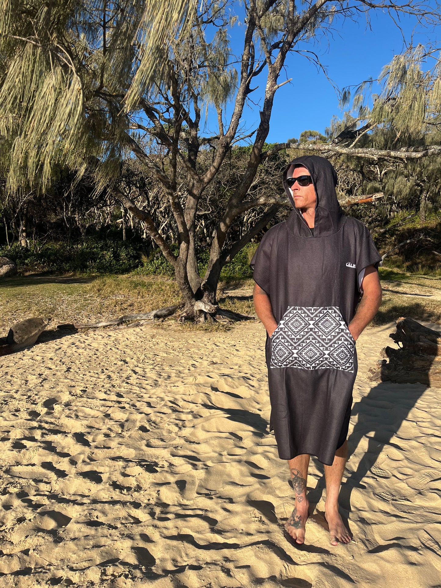 Person standing on a rocky beach in a black hoody beach towel