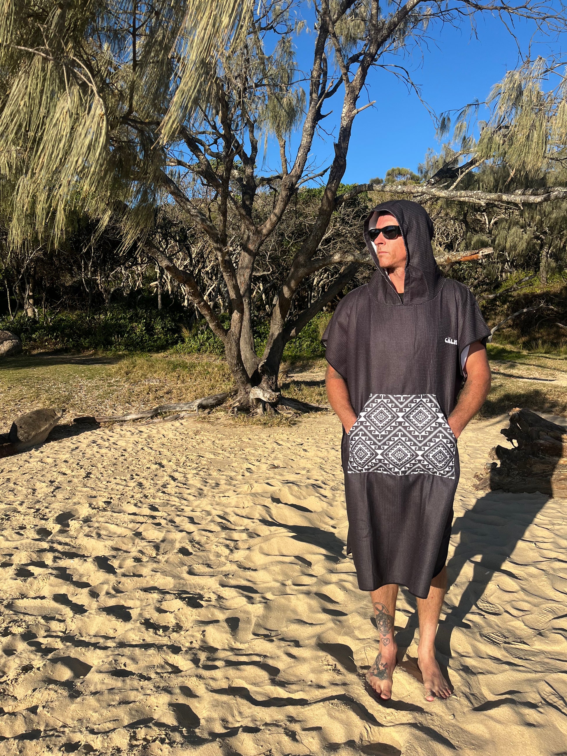 Person standing on a rocky beach in a black hoody beach towel