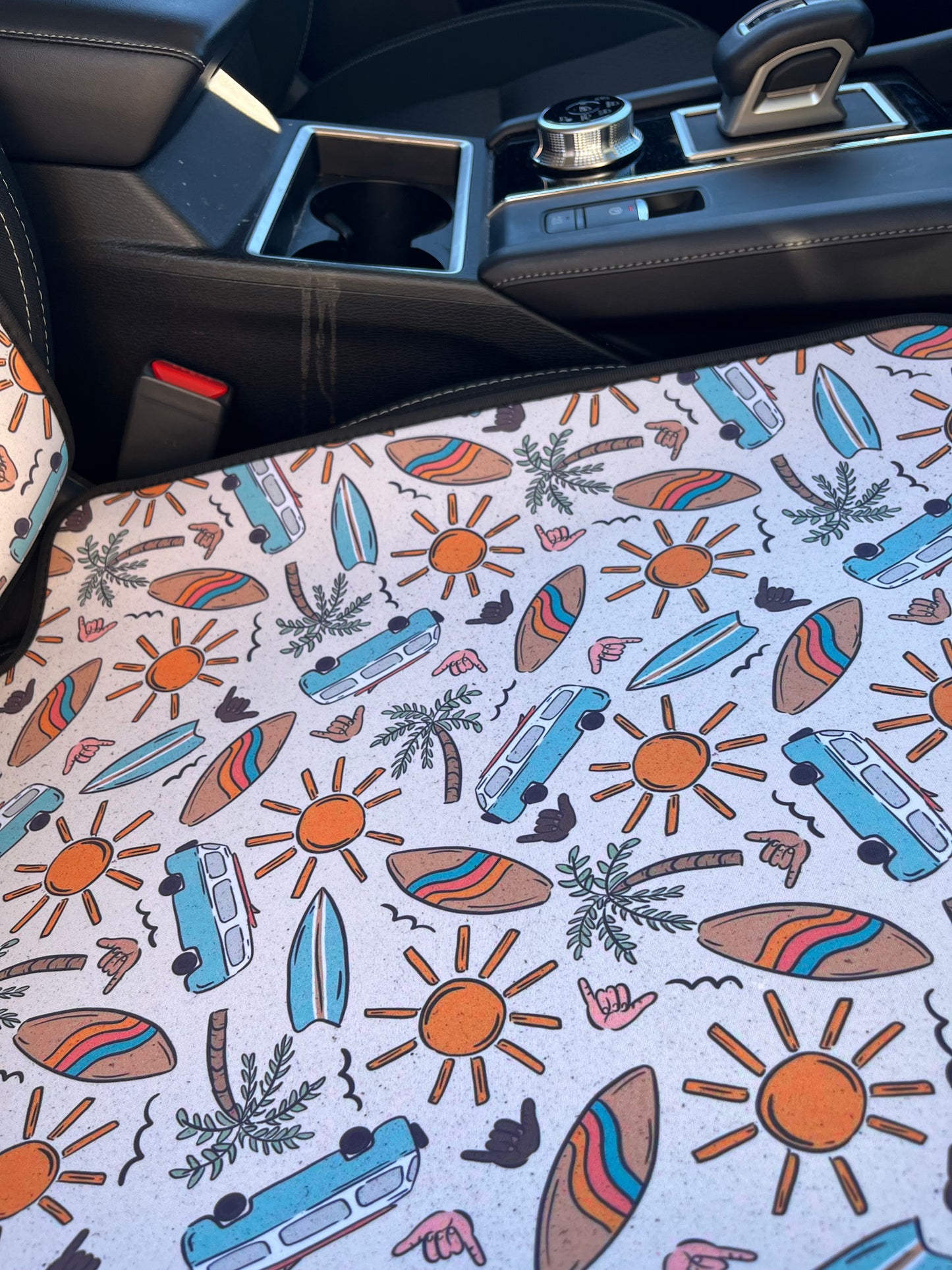 Combi vans, suns, palm trees, and surfboard print in tans/browns, yellow and aqua. Shown on car seat