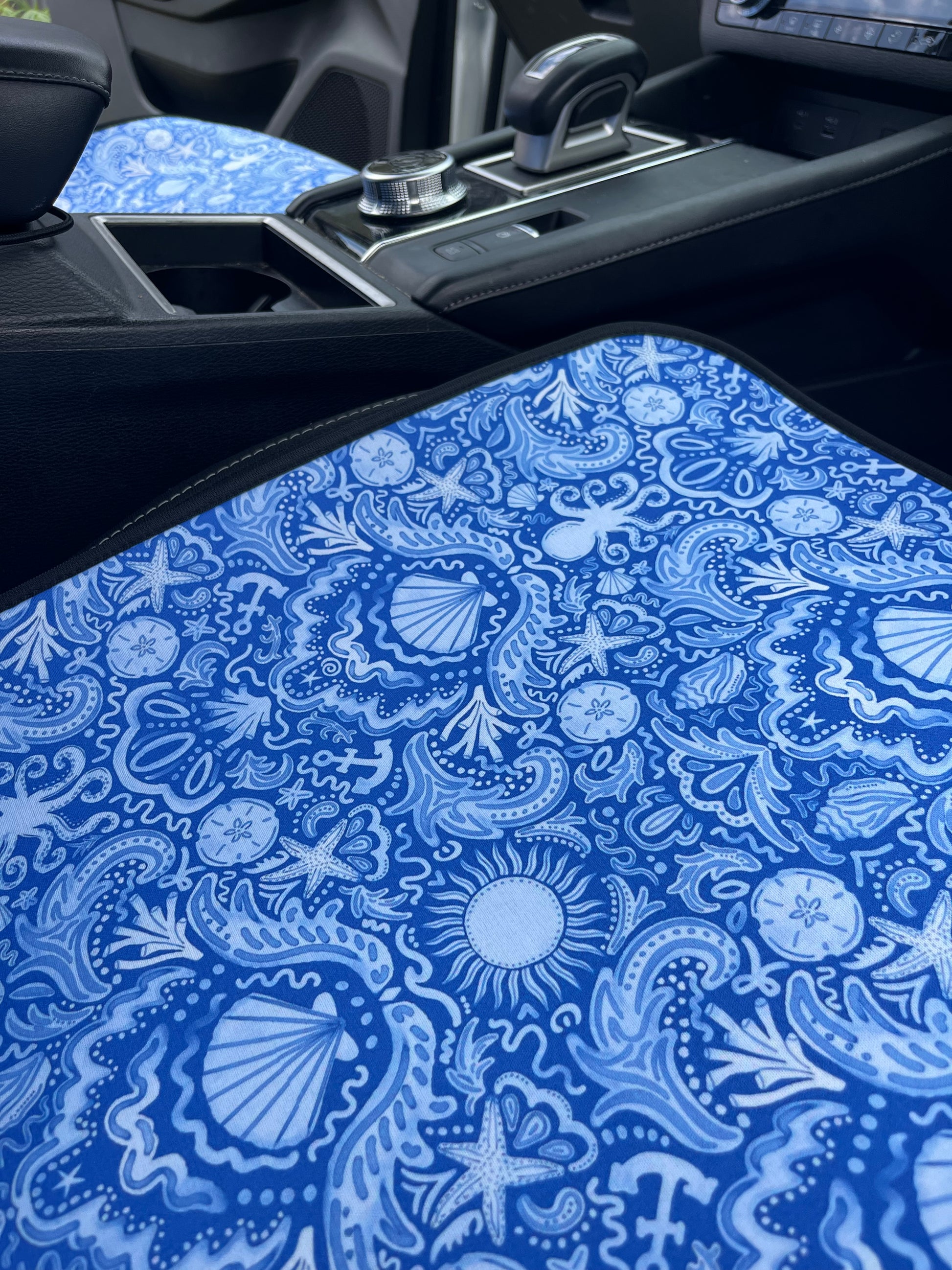 Close-up of a blue patterned seat cover with marine designs in a car.
