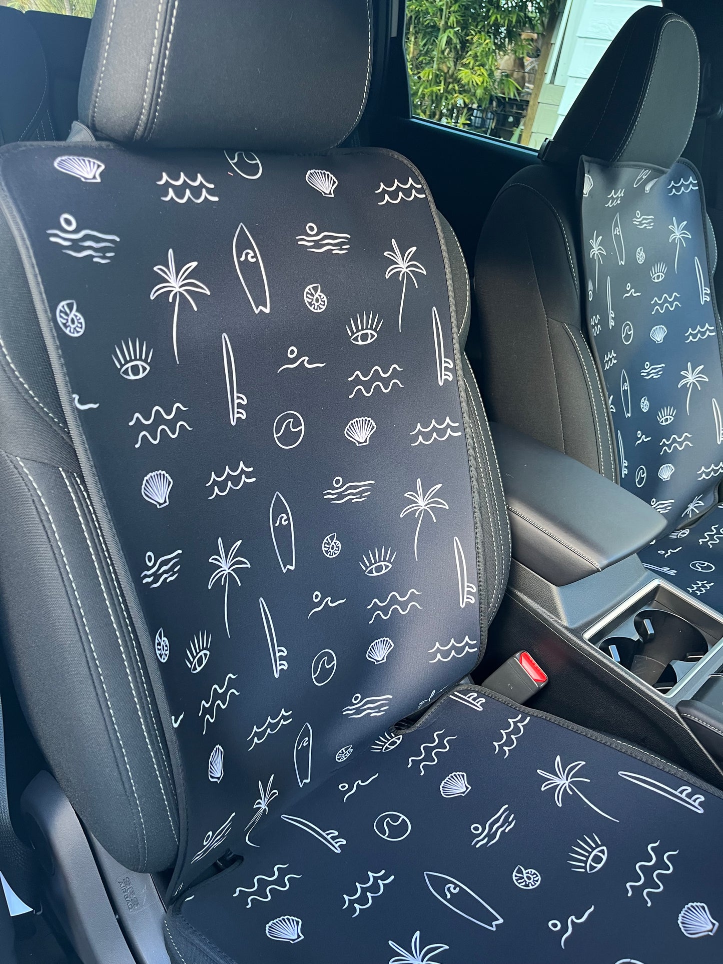 Black and white surf print. Includes surfboards, shells, palm tree, and waves. Set of two shown on the front seats. Easy to install made out of neoprene