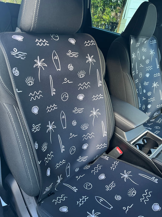 Black and white surf print. Includes surfboards, shells, palm tree, and waves. Set of two shown on the front seats. Easy to install made out of neoprene