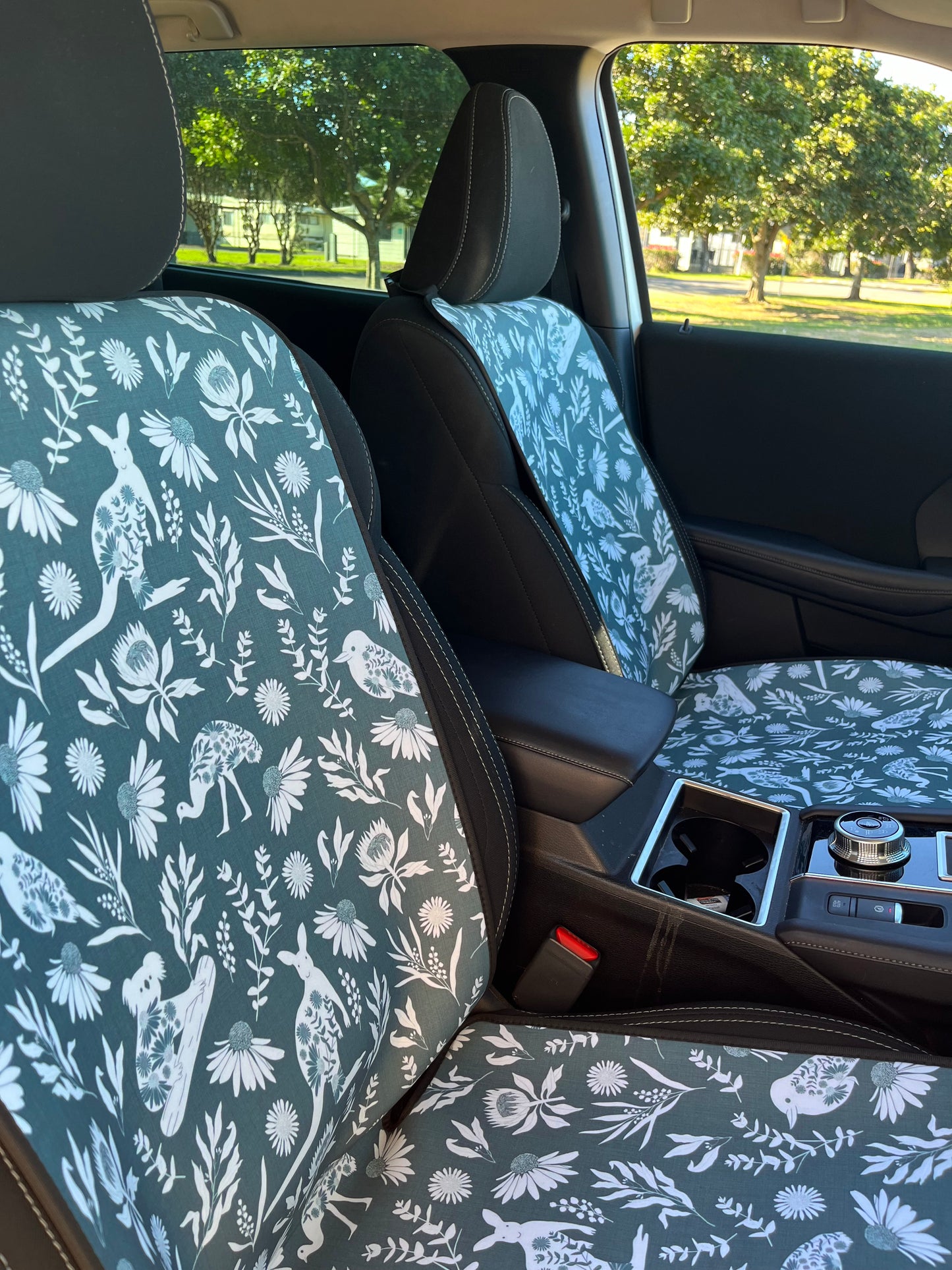 Car seat covers in sage green with the print of Australian animals, shown on the front car seats. 
