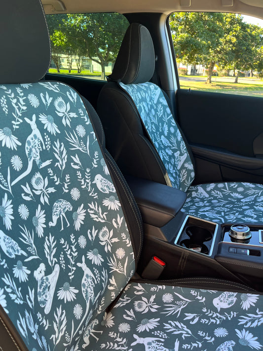 Car seat covers in sage green with the print of Australian animals, shown on the front car seats. 