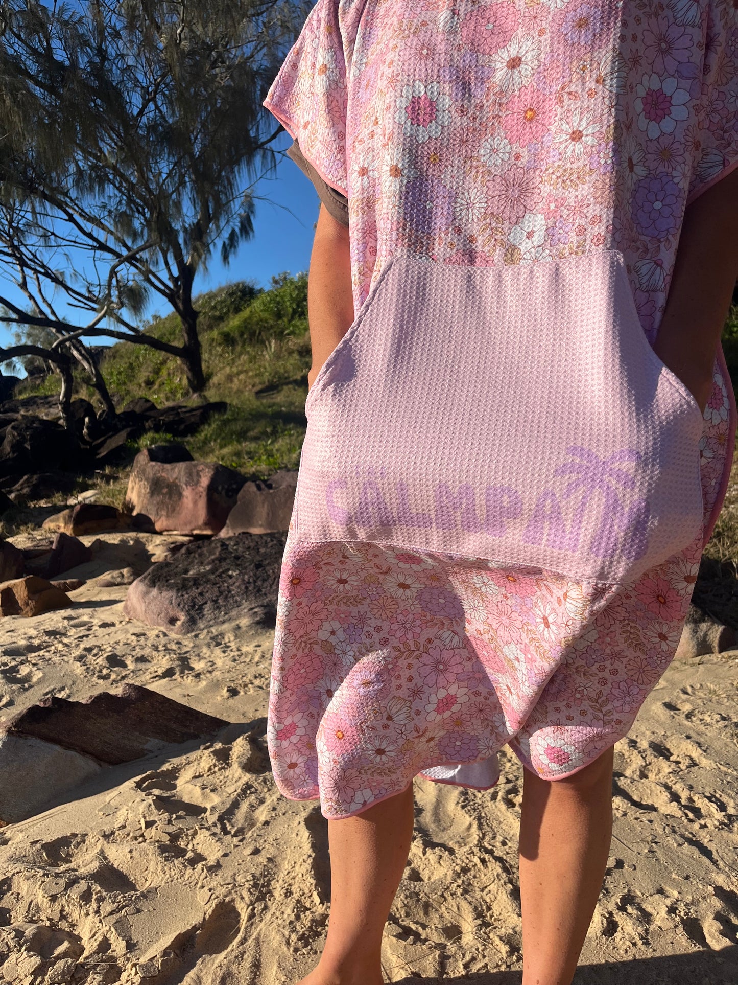 Person wearing a floral hooded towel with a blurred background of trees and rocks