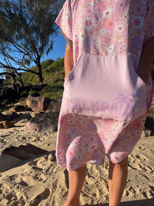 Person wearing a floral hooded towel with a blurred background of trees and rocks